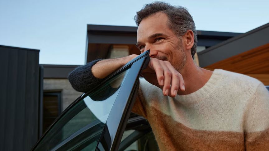 Ein Mann lehnt an der Fahrertür eines Audi