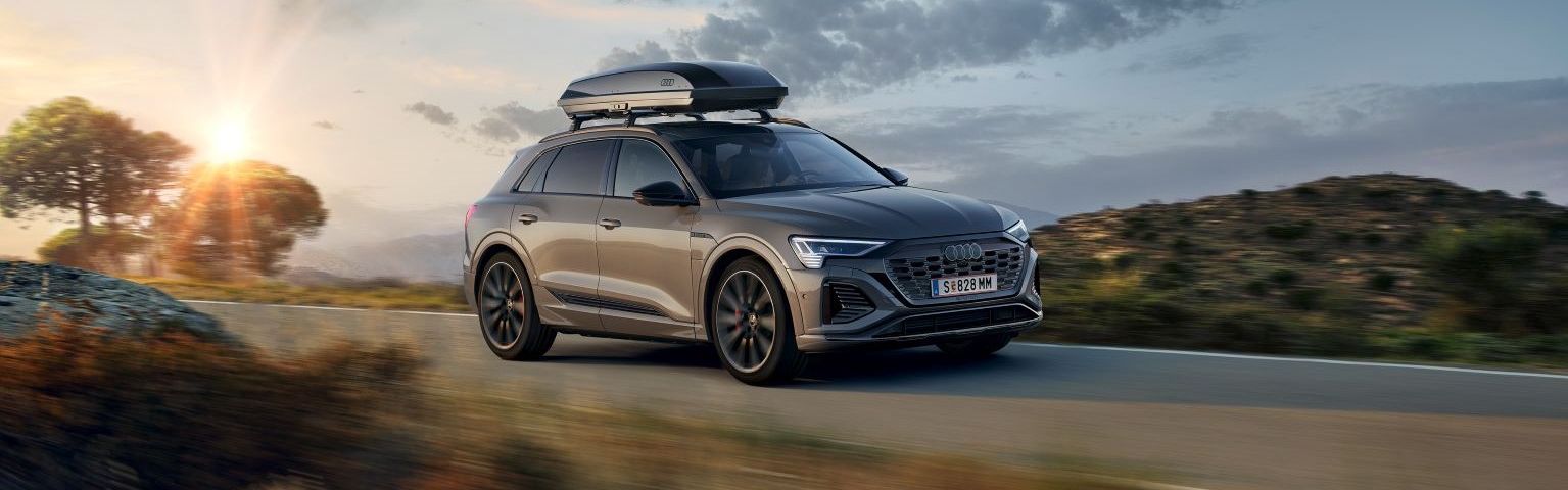Ein Audi Q8 mit Dachbox in Fahrt auf einer Landstraße.