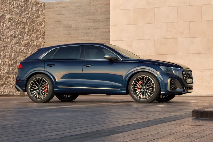 Der Audi SQ8 SUV in Seitenansicht auf einem Parkplatz, umrahmt von hohen Mauern.