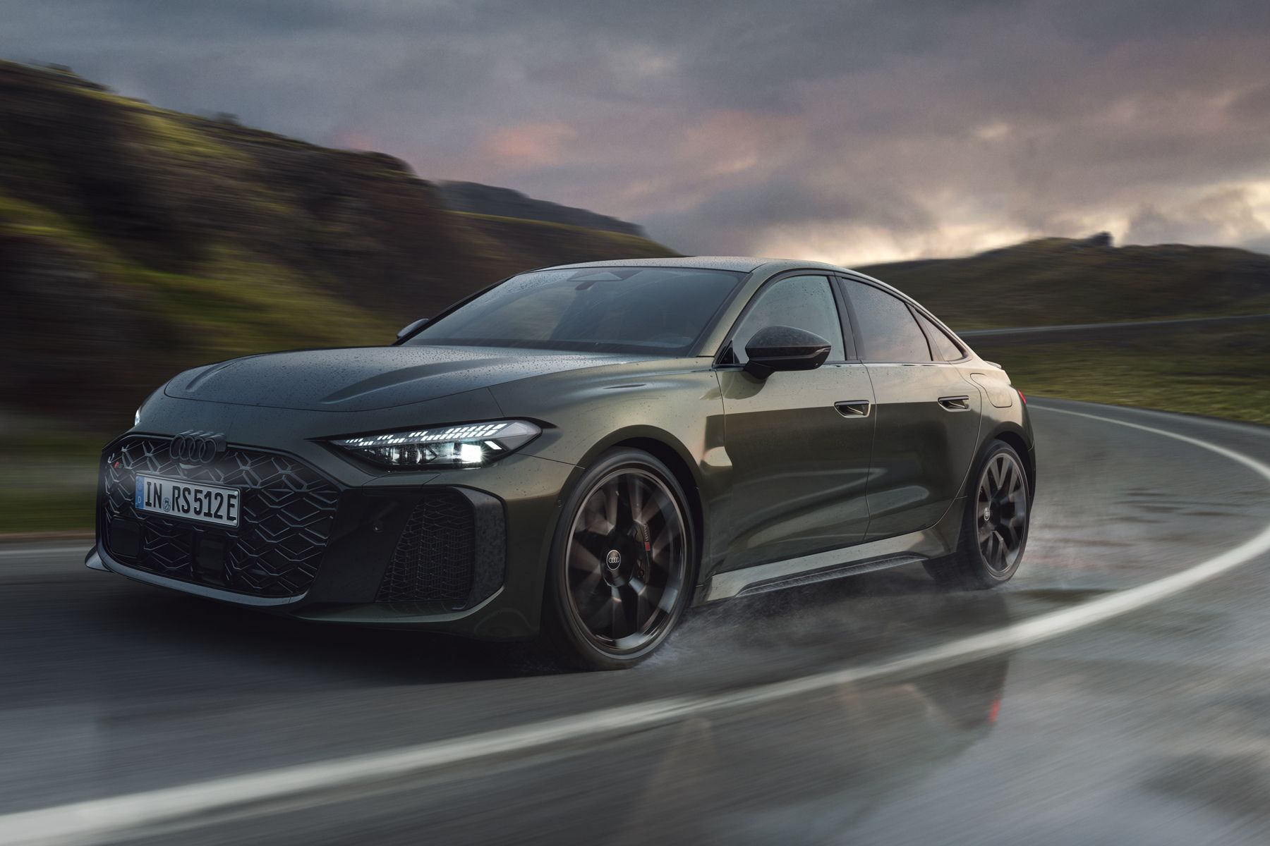 Die RS 5 Limousine schräg von vorn fährt eine Kurve auf einer Gebirgsstraße.