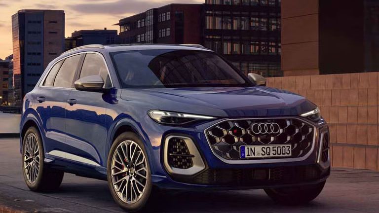 Der SQ5 SUV steht vor der Skyline einer Küstenstadt. Davor befindet sich eine junge, modische Frau. 