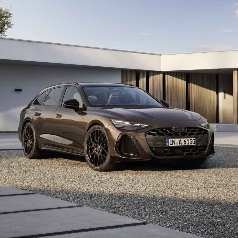 Der A6 Avant steht im schrägen Frontprofil auf einer Kiesfläche vor einem modernen Haus. Die Frontscheinwerfer des Fahrzeugs zeigen eine Lichtsignatur.