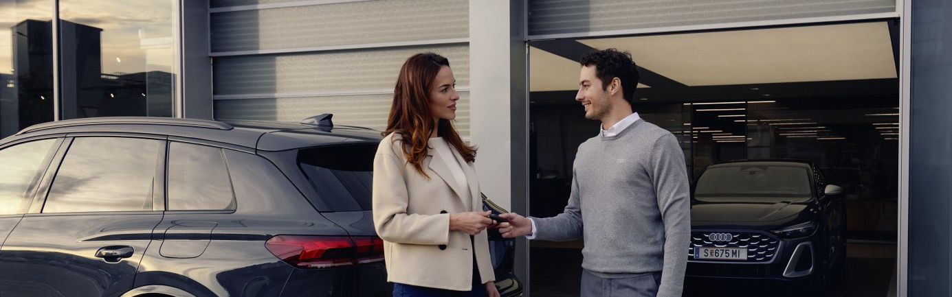 Ein Audi Mitarbeiter übergibt einer Kundin die Autoschlüssel für ihren Audi.