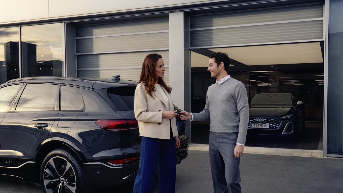 Ein Audi Mitarbeiter übergibt einer Kundin die Autoschlüssel für ihren Audi.