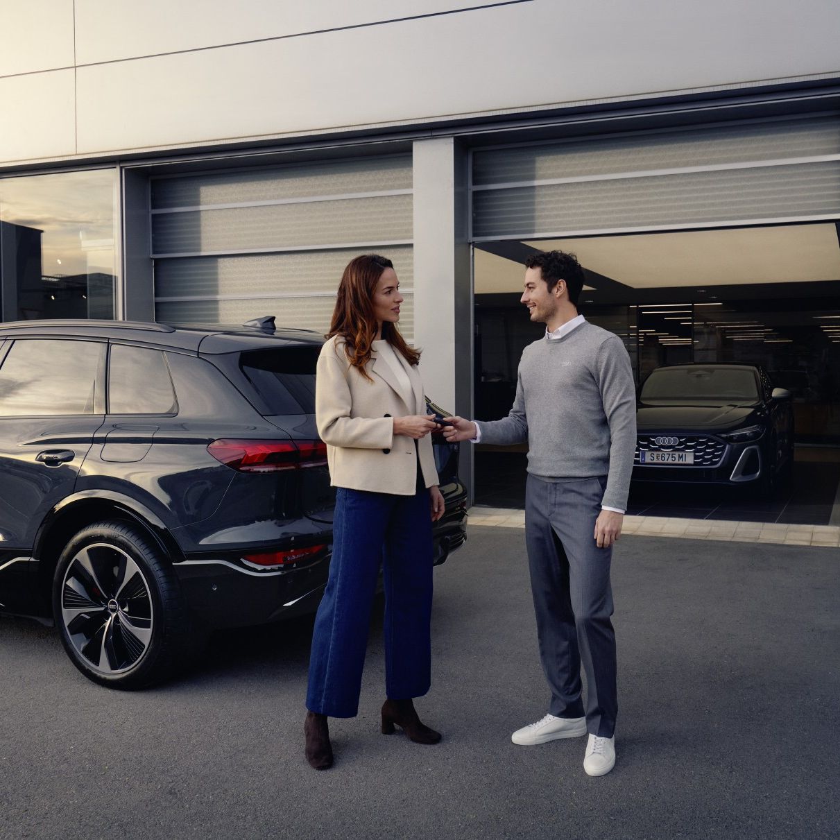 Ein Audi Mitarbeiter übergibt einer Kundin die Autoschlüssel für ihren Audi.