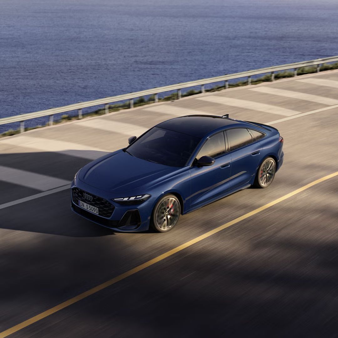 Die S5 Limousine von schräg oben. Sie fährt auf einer Straße entlang der Küste. 