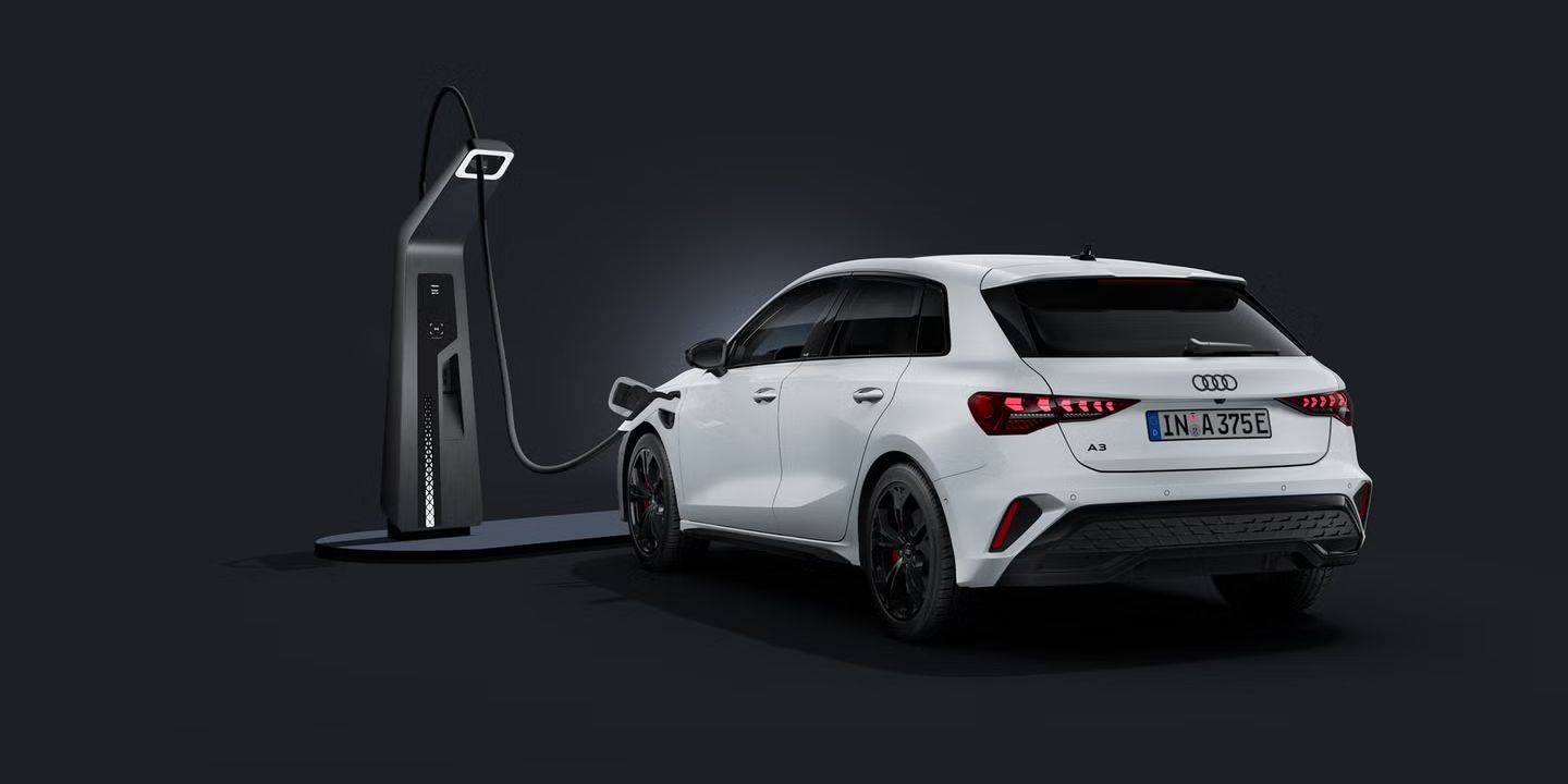 Ein Audi A3 Sportback e-hybrid, schräg von hinten auf dunklem Hintergrund, angeschlossen an eine Schnellladestation.