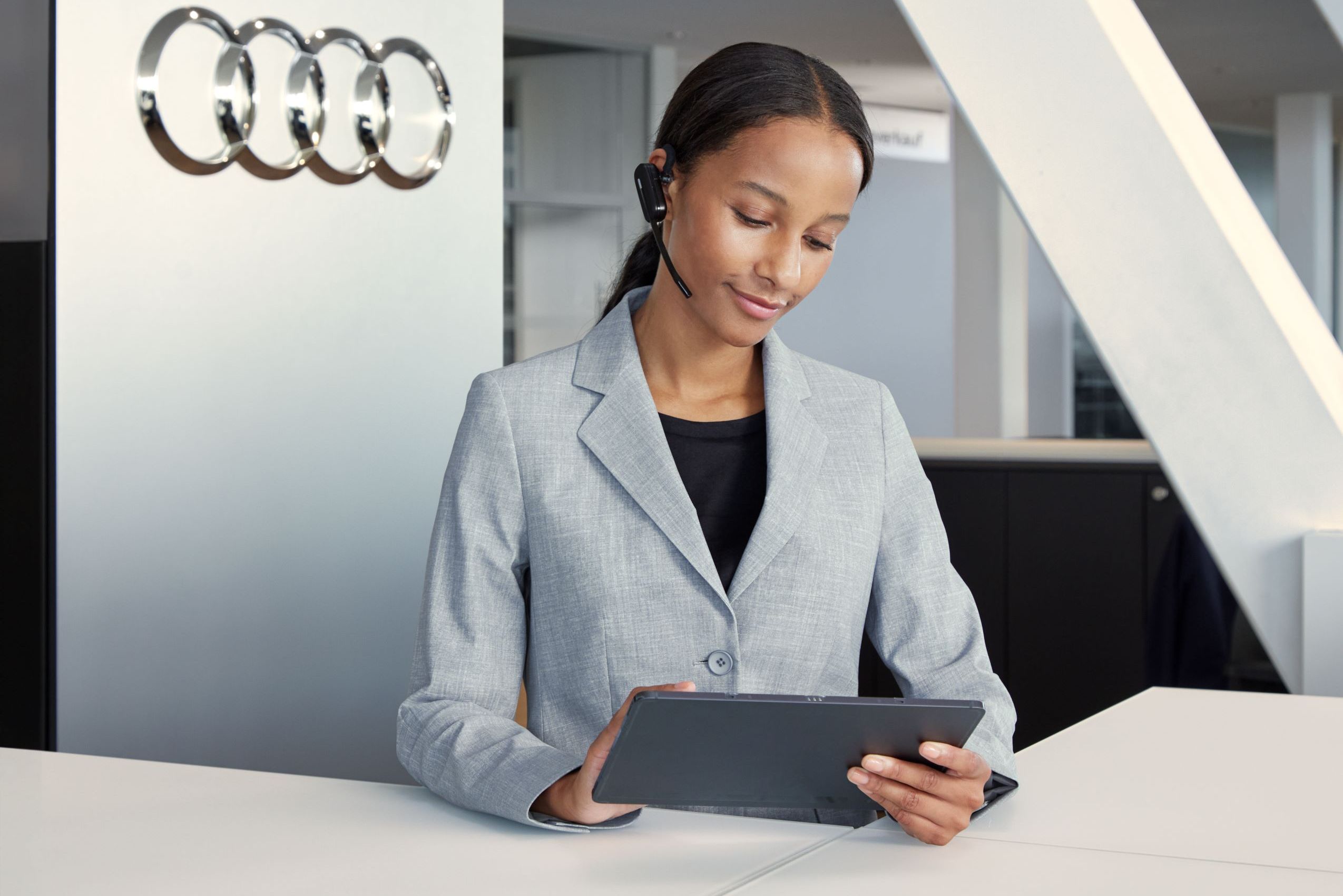 Eine Audi Service Mitarbeiterin blickt auf ihr Tablet